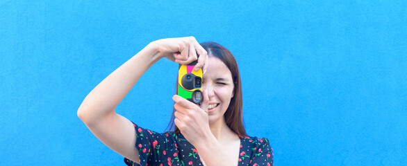Funny caucasian girl in casual outfit is taking a pictures with a vintage camera outdoor - Summer,...