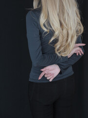 Woman with blond long hair hugs herself on a dark background. Mental health concept.