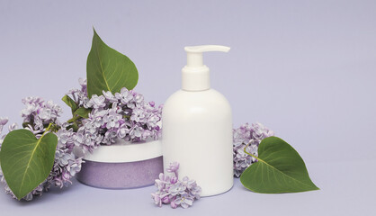 Group of cosmetic bottles with lilac on background.  Face scrub, gel shower and cream on violet background with lilac flowers.