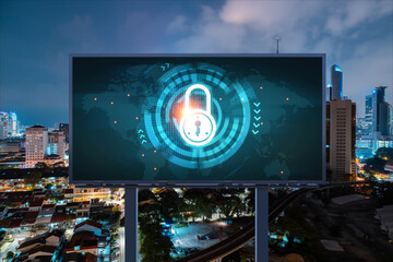 Padlock icon hologram on road billboard over panorama city view of Kuala Lumpur at night to protect business, Malaysia, Asia. The concept of information security shields.