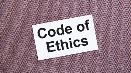 On a brown background, a white rectangular card with the text CODE OF ETHICS
