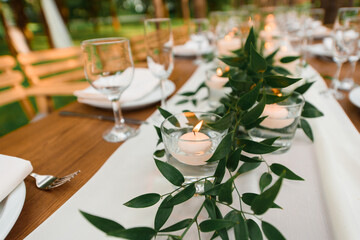Rustic green branch and candles on the table. Wedding decoration.