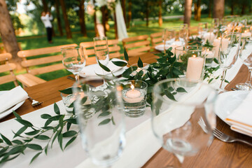 setting a wedding banquet in the forest. Rustic style. Green branch and candles. Celebrating a wedding