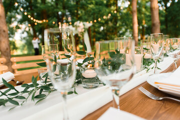 setting a wedding banquet in the forest. Rustic style. Green branch and candles. Celebrating a wedding