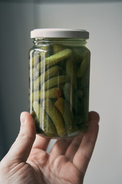 hand holding small glass jar full of pickles