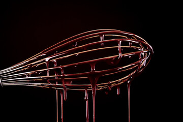 Melted chocolate flows down the wisk. Melted dark premium chocolate on a brown background. Belgian...