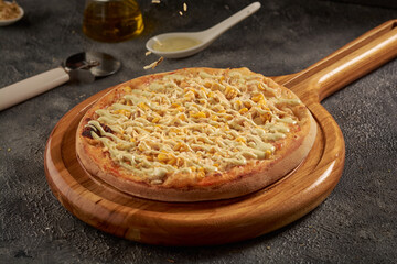 Delicious pizza with cheese and maize on a wooden board