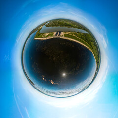 little planet aerial drone panorama 360 view of the Shapshugskoye reservoir with dark water, spillway sluice and the Kuban river on a spring sunny day