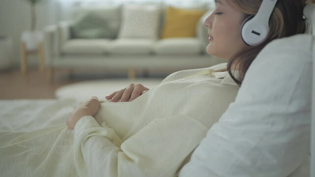Pregnant woman concept of 4k Resolution. Asian girls are lying listening to music in their bedrooms.