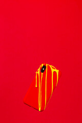 Yellow painting melting on an Smartphone with Red case against a red background