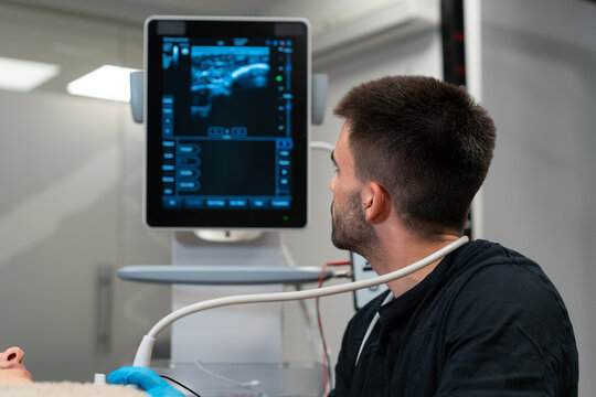 Male doctor checking up chest of woman on monitor of ultrasound machine in hospital