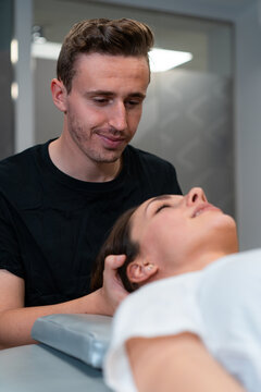 Unshaven male physical therapist massaging neck of woman with closed eyes in hospital