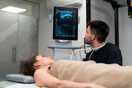 Male doctor checking up chest of woman on monitor of ultrasound machine in hospital