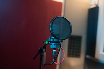 Pop filter and modern dynamic mic with wires in empty sound studio on blurred background