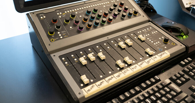 Modern audio mixer with button control panel against computer keyboard on table in sound studio