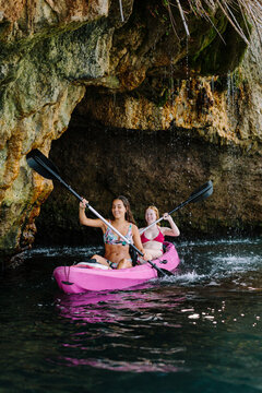 Side view travelers with paddles floating on turquoise seawater near the rocky shore on sunny day in Malaga Spain