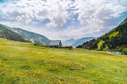 Scenic view of countryside constructions on hillside between majestic mountains in Aran Valley in Lleida Catalonia Spain in summer