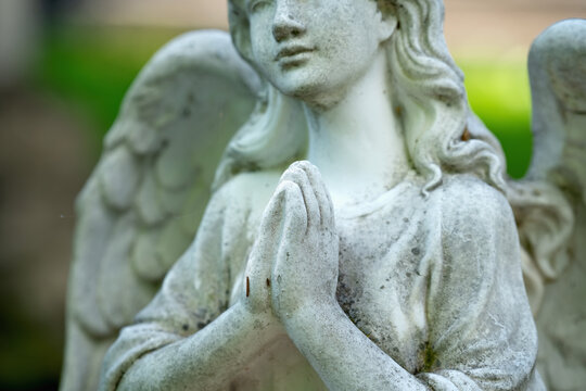 Tender beautiful angel praying. Fragment of an  ancient statue. Selective focus on hands.