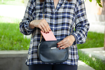 woman hand phone in bag in street