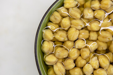 Chickpeas soaked in water, in bowl, on marble table. Concept of healthy eating, veganism, vegetarianism, meat and egg replacement. Prepare chickpeas before making hummus and other legume dishes