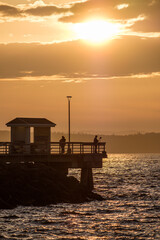 A silhouette of a ferry and a fishing pier at sunset