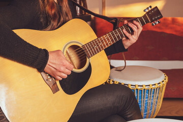 Hands of a young woman playing acoustic guitar