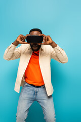 african american man adjusting vr headset on blue background