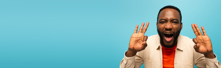 thrilled african american man showing okay signs isolated on blue, banner