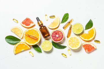 Vitamin C. Fresh citrus fruits with serum bottles, ampoules and pills. Top view with copy space.