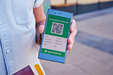 Smartphone in hand displaying on app mobile valid digital green vaccination certificate for Covid-19. Immunity vaccine passport, vaccination certificate, health passport for new normal travel