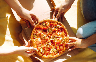 Hands taking slices of pizza close view. Friends eating pizza at the beach. Fast food concept....