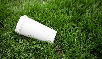 White paper coffee cup littered on grass. 