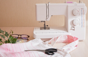 eco shopping bag made of cotton fabric, sewing machine, scissors, glasses and spools of thread on...
