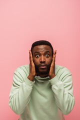 Excited african american man with hands near face looking at camera isolated on pink