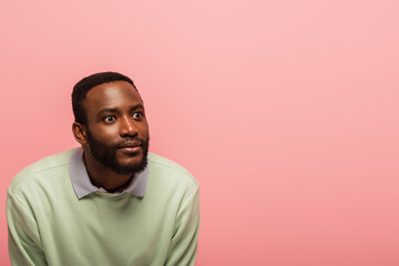 African american man in green jumper looking away isolated on pink