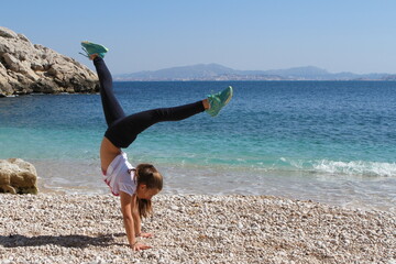 jeune fille pratiquant de la gymnastique sur une plage - 434177491