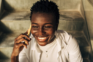 black woman smiling talking on her cell phone. African girl sitting communicating on her cell phone. Communication concept.