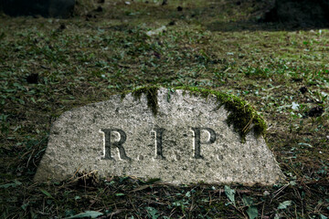 Old tombstone with R.I.P. inscription engraved. Mossy grave on ancient cemetery area. Rest in peace.