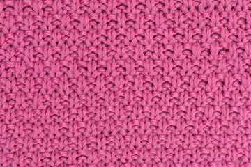 Pink knitted fabric pearl woolen background. The structure of the fabric with a natural texture. Fabric background. Knitted woolen background.