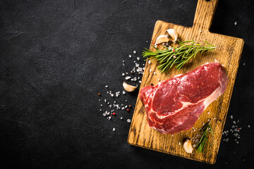 Beef steak ribeye. Fresh raw meat at black background. Dry aged meat. Top view image with copy...