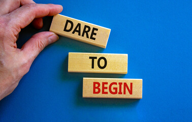 Dare to begin symbol. Wooden blocks with words 'Dare to begin'. Beautiful blue background, businessman hand. Business, dare to begin concept, copy space.