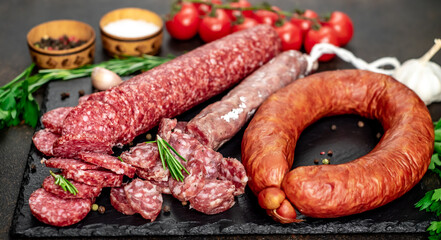 Assortment of smoked sausages and sausages with mold on a stone background