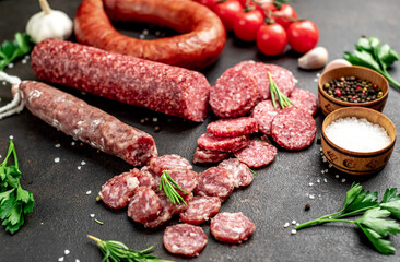 Assortment of smoked sausages and sausages with mold on a stone background	