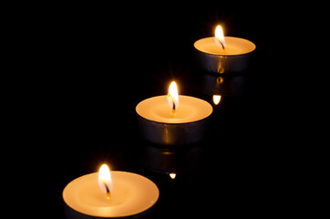 Fototapeta na wymiar Group of burning candles on black background.