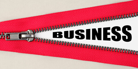 On a gray background, a red zipper unfastens, on a white surface the inscription - BUSINESS