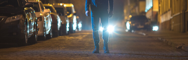 The man stand outdoor on the background of a headlight. Evening night time