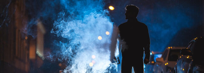 The man stand near the smoke. Evening night time. Telephoto lens shot