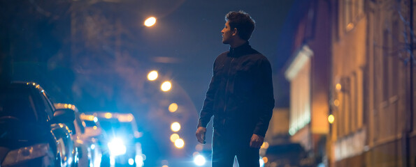 The man stand on the road. Evening night time. Telephoto lens shot