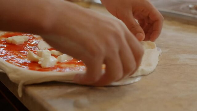 Chef preparing neapolitan margherita pizza with tomato sauce and mozzarella cheese, taking raw dough with ingredients into the oven.