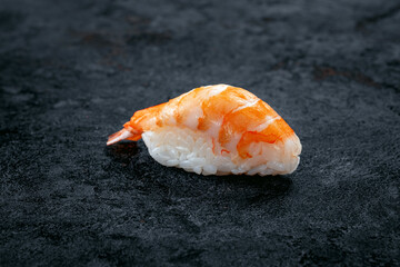 One nigiri sushi with prawn on a stone dark background. Japanese dish sushi ebi
